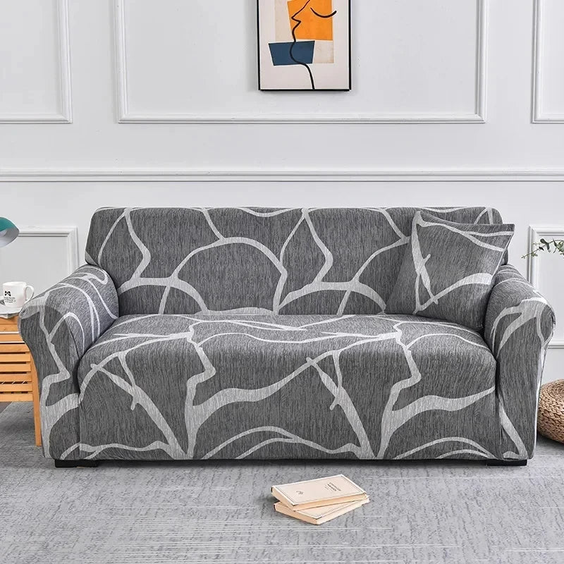 A gray elastic sofa cover protector featuring a white abstract floral print on a light gray fabric.