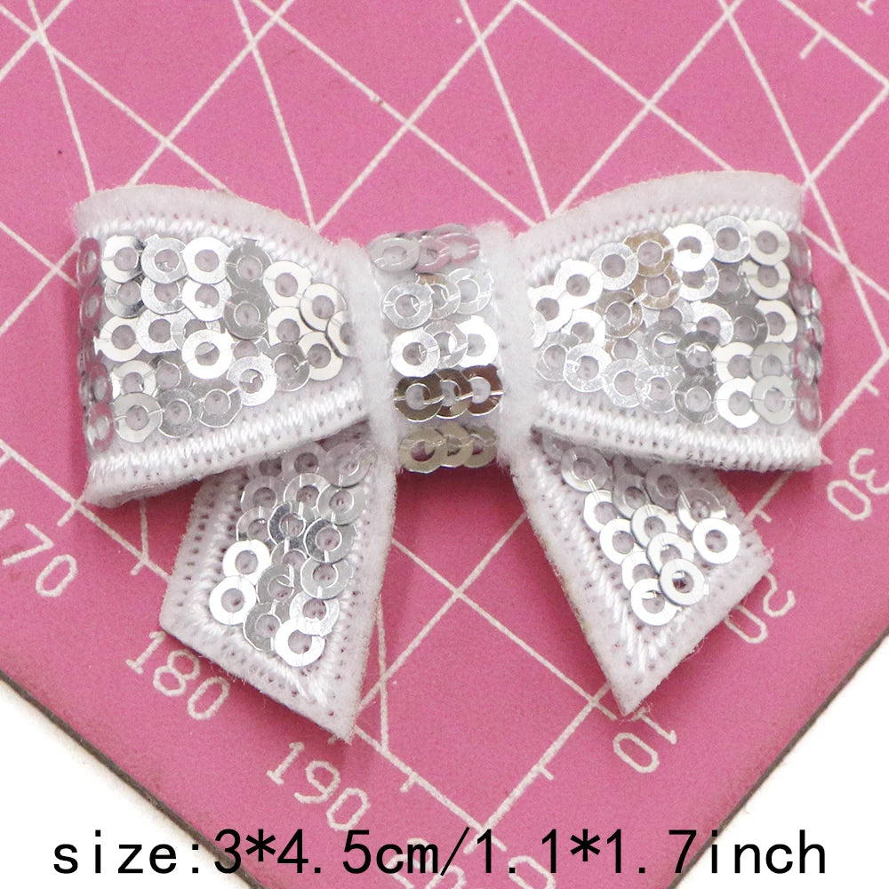 Silver sequin bow patches for DIY decoration shown on a pink background with a ruler.