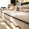 A beige pleated sofa cover with black trim and striped texture is displayed indoors near a window.