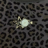 A gold-toned star-shaped pocket watch keychain with an adjustable clock face set against a leopard print background.