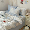 A set of three light blue floral duvet covers and pillowcases displayed on a bed.