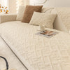 A beige textured sofa cushion cover with a brown accent pillow and a cup on the fabric.