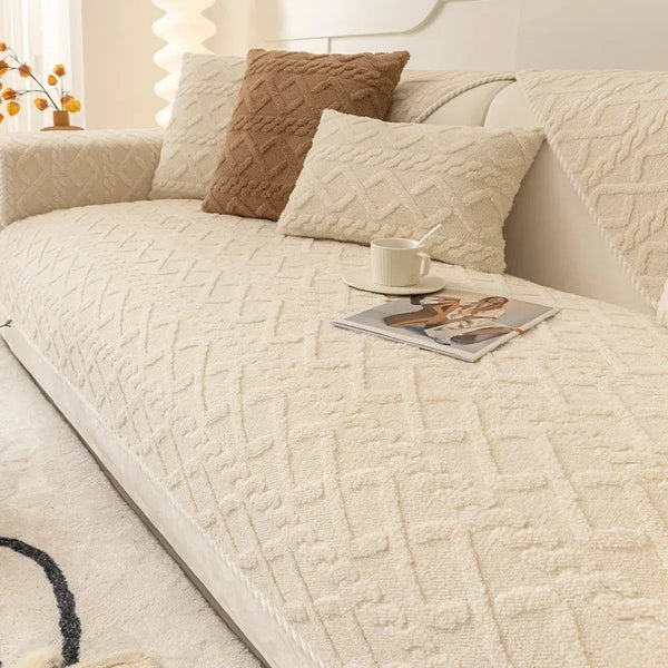 A beige textured sofa cushion cover with a brown accent pillow and a cup on the fabric.