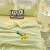 A light green Korean style seersucker summer quilt set with yellow accents and a pillow that reads You Matter.