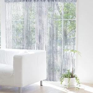 White decorative door string curtains covering a window with sheer vertical strands and green foliage visible outside