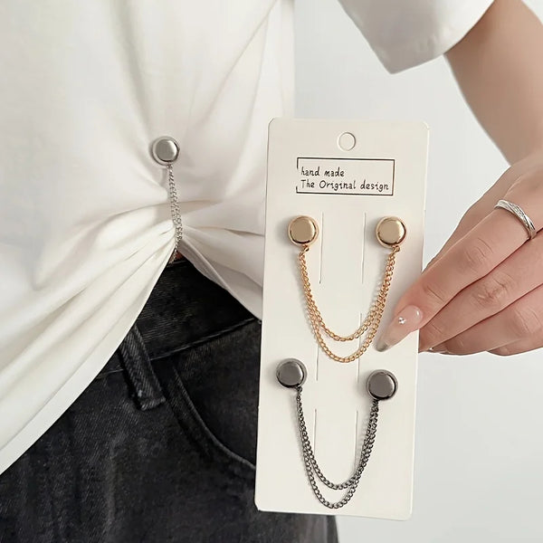 A hand shows a pair of gold-toned chain and magnetic buttons for clothing adjustment on a white tag.