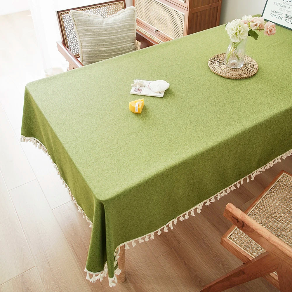 A lime green textured cotton table runner displayed on a wooden table with white tassels.