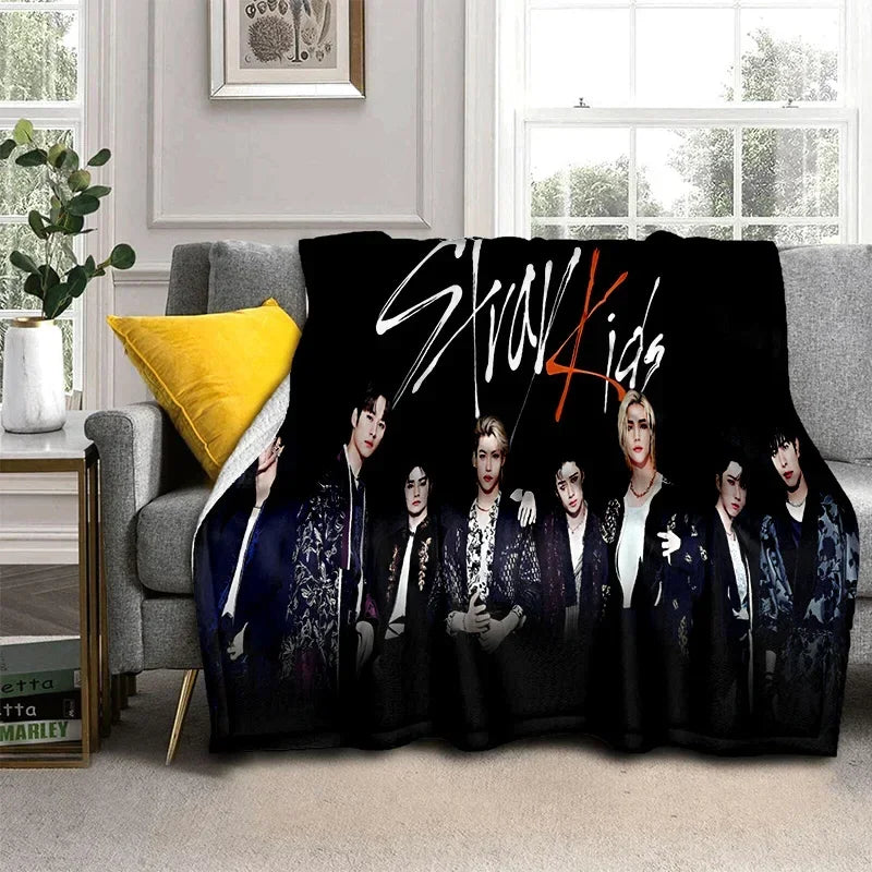 A black fleece throw blanket featuring a photo of the Stray Kids Kpop group members.