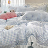 A light blue and white gingham duvet cover set featuring a pink elephant and a beige stuffed animal on a bed.