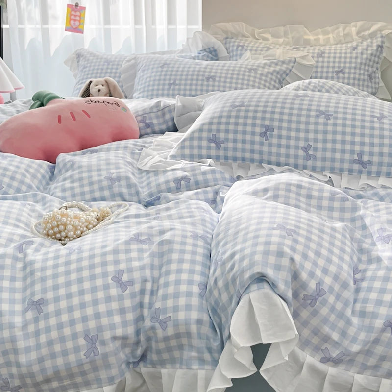 A light blue and white gingham duvet cover set featuring a pink elephant and a beige stuffed animal on a bed.