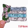 A set of embroidered letter iron-on patches featuring floral designs and text on a light blue fabric background.