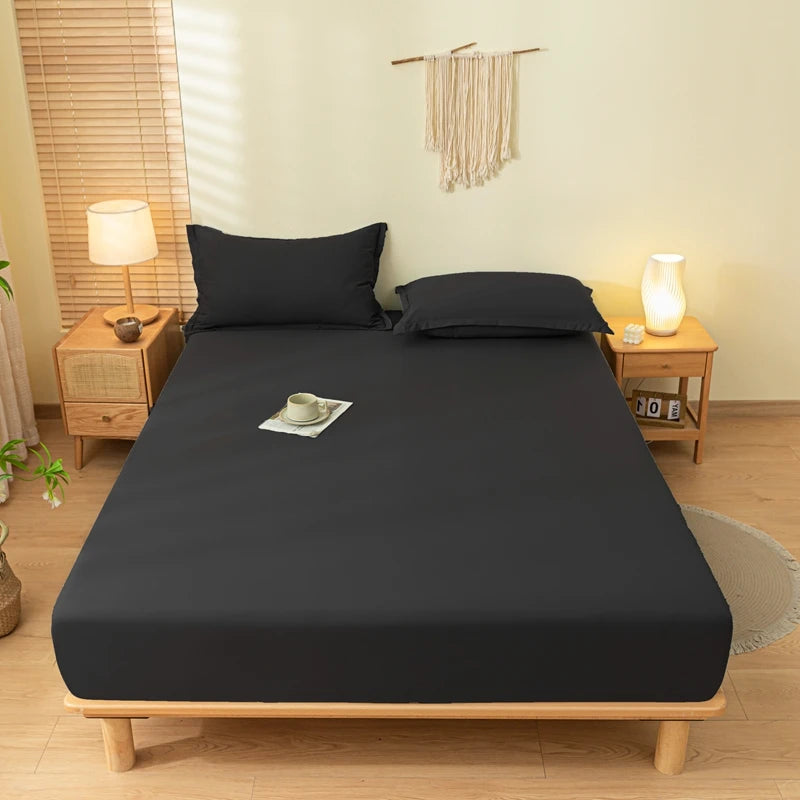 A dark gray fitted bed sheet set is laid out on a wooden bed frame in a bright bedroom.