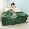 A dark green flannel cloak with a white and black leaf pattern is draped over a white bed.