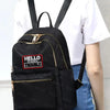 Black backpack with gold accents and a red patch that says HELLO MY NAME IS TROUBLE