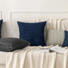 A sofa decorated with various indigo and beige textured throw pillows.