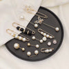 Gold-toned adjustable pearl brooches featuring floral and round designs displayed on a black plate.