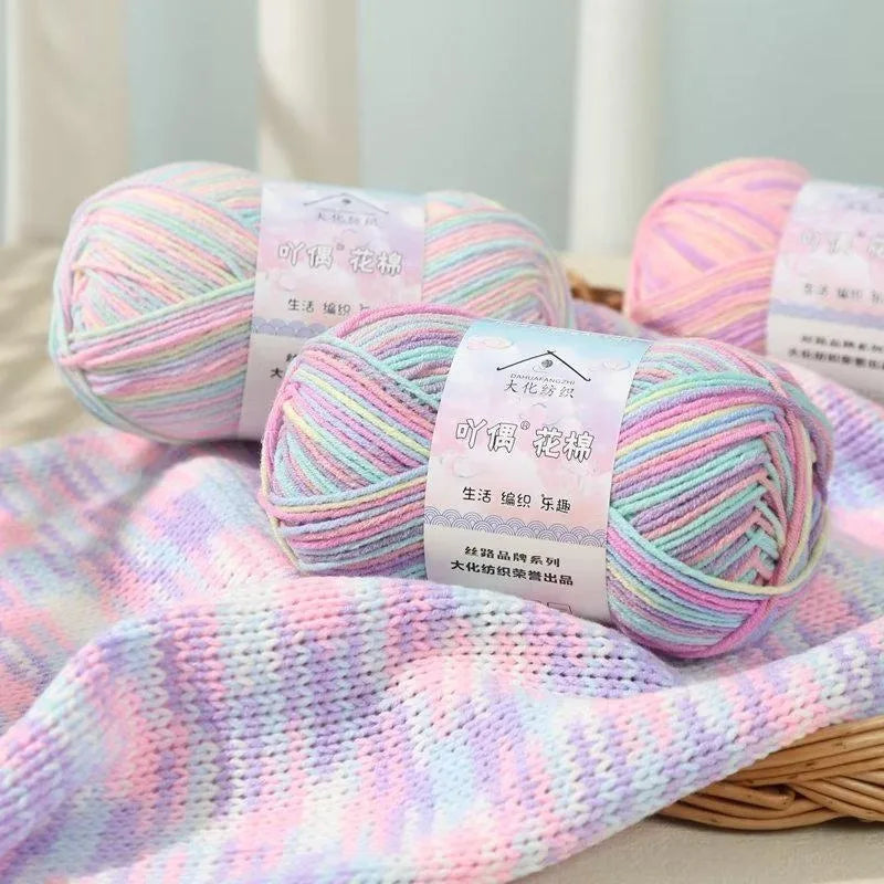 A ball of pink and green gradient yarn is displayed next to a knitted fabric swatch.