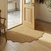 A natural jute non-slip entrance door mat placed on a light wood floor next to a wooden chair and a glass-paned door.