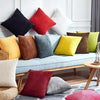 A collection of colorful velvet and corduroy cushion covers displayed on a light blue sofa.
