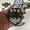 A hand holds a military style embroidered patch featuring stars and stripes on a dark olive green fabric.