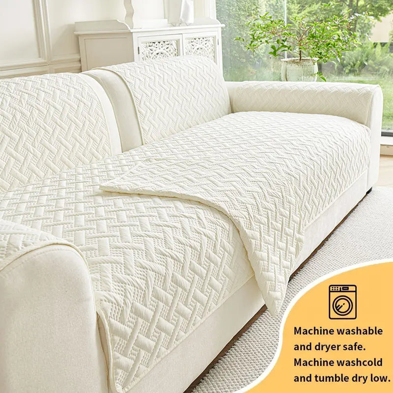 A cream quilted sofa cushion with a removable cover shown on a light gray sofa.