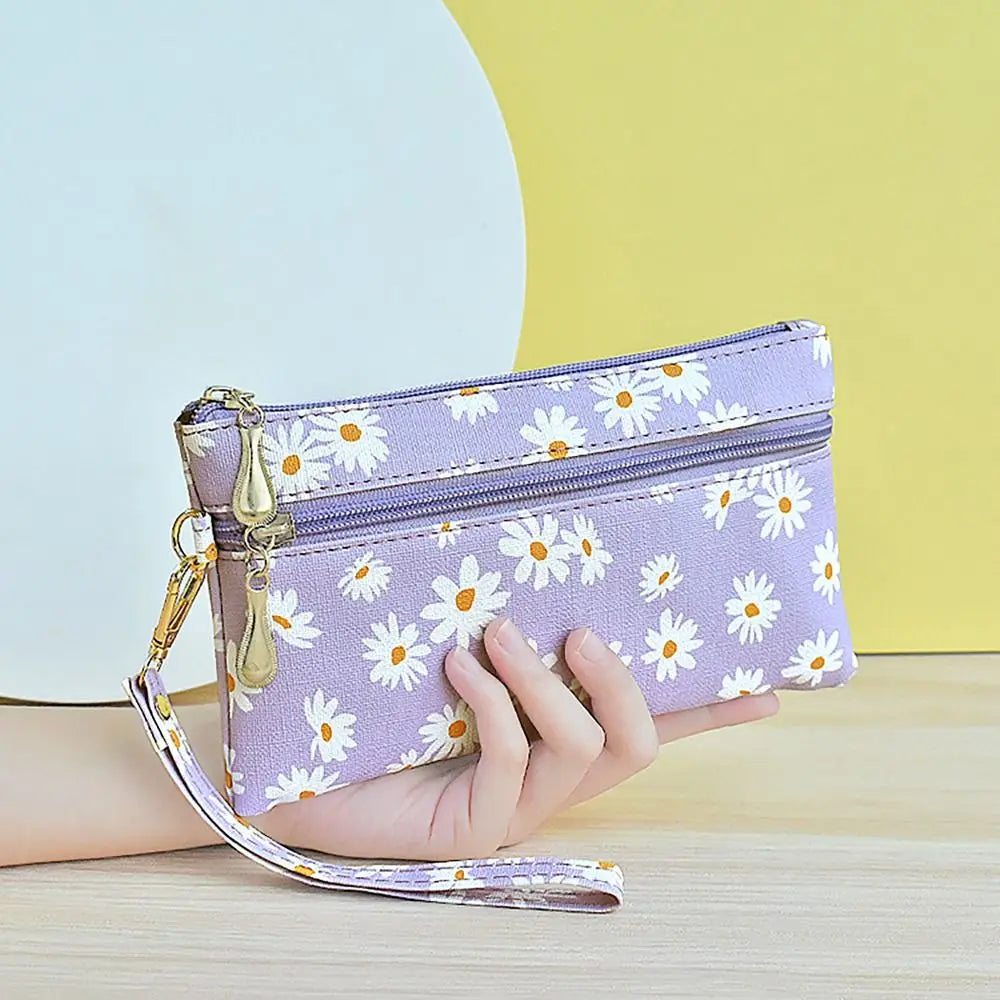 A hand holds a purple PU leather coin purse with a floral pattern against a yellow background.