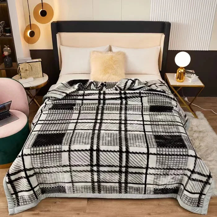 A black and white plaid blanket with a cream fluffy pillow displayed on a bed.