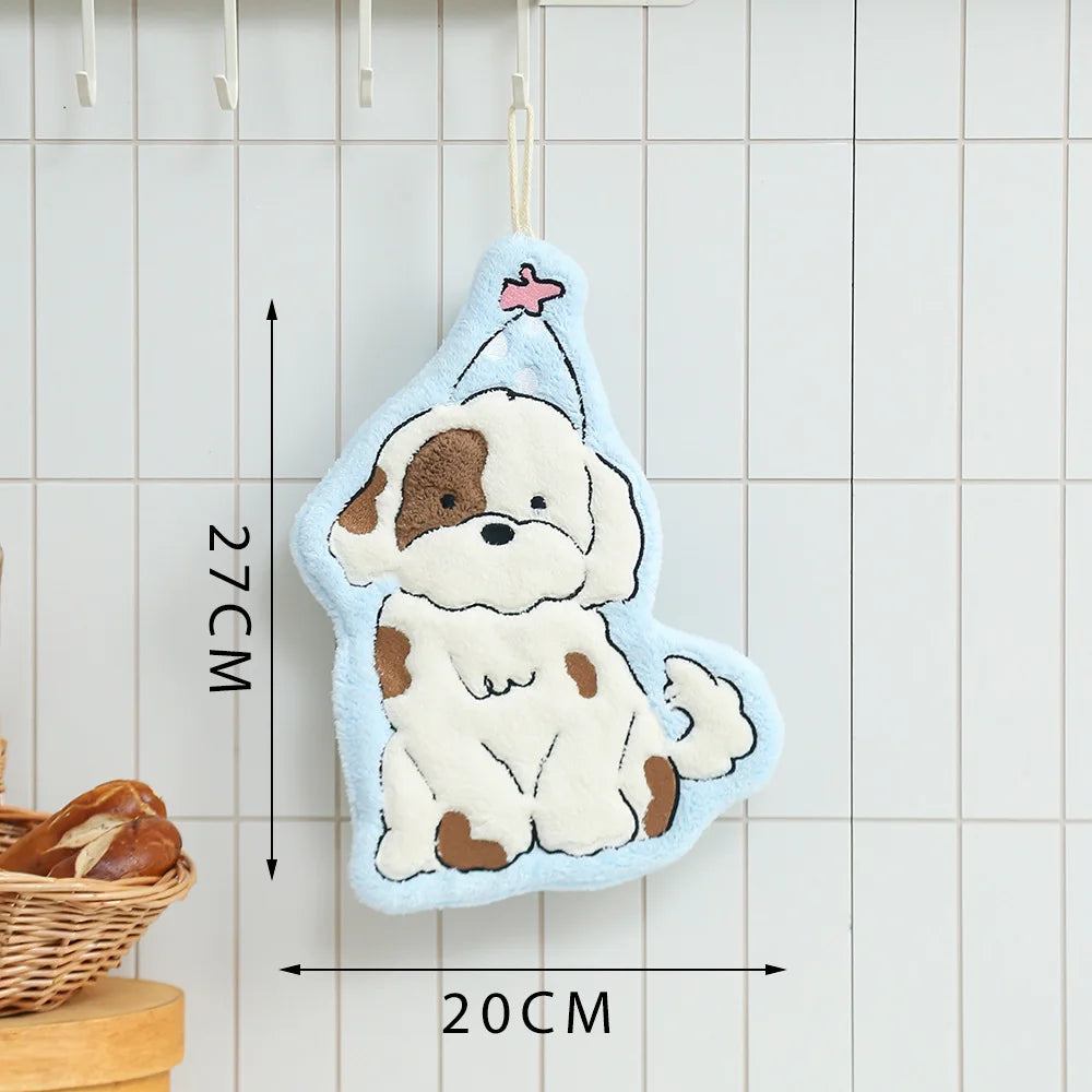 A cute cartoon dog hand towel in light blue and cream colors is hanging against a white tiled background.