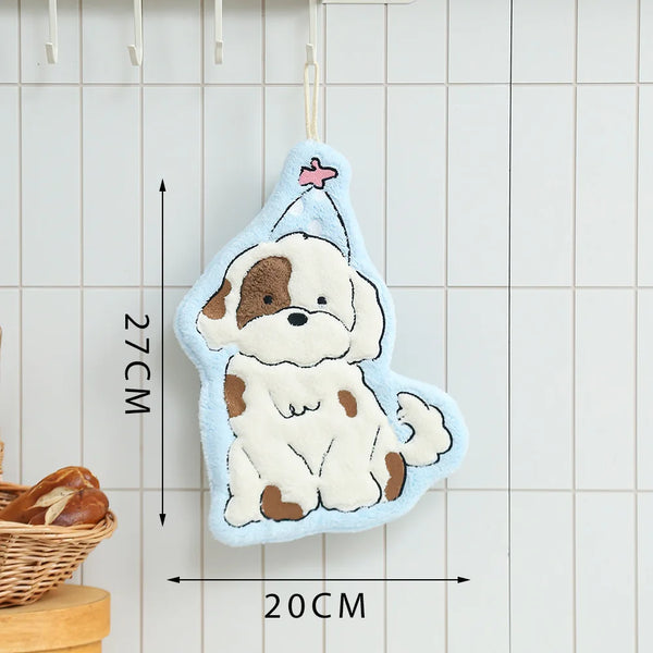 A cute cartoon dog hand towel in light blue and cream colors is hanging against a white tiled background.