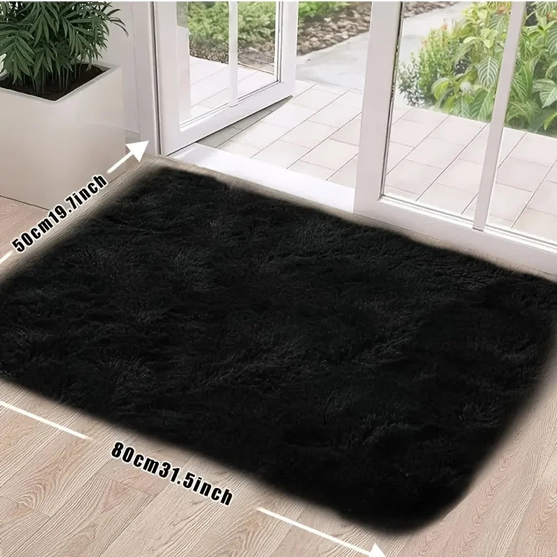 A rectangular black faux fur rug placed on a light wood floor near a glass door.