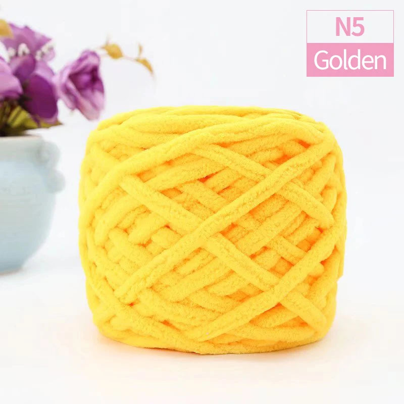 A ball of bright yellow chunky velvet knitting yarn with an open, crisscross knit pattern.