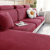A deep red textured sofa seat cushion cover with a quilted pattern and a white decorative pillow on a light-colored sofa.