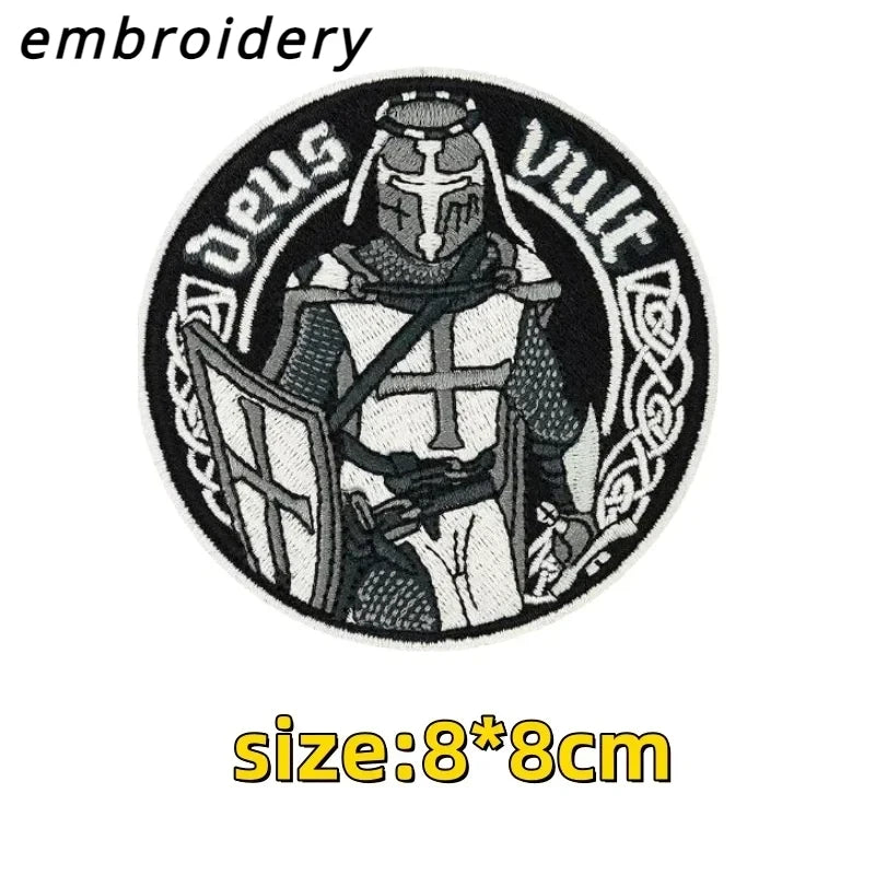 Black and white embroidery of a warrior figure wearing a helmet and armor on an oval patch.