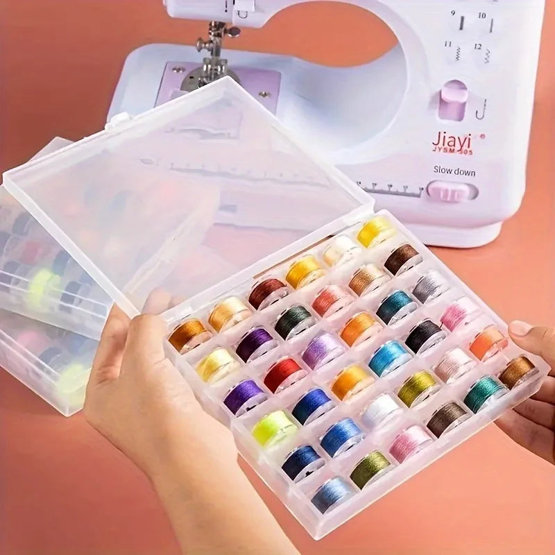 A hand holds an open plastic box filled with numerous colored sewing machine bobbins and thread.