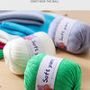 A collection of soft and firm colored acrylic yarn skeins, including light blue, white, purple, and bright green, laid out on