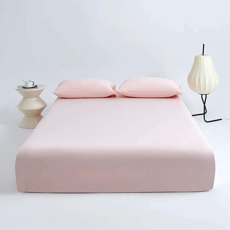 A set of pink ice silk cooling fitted bed sheets displayed on a white bed with two matching pillows.