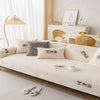 A beige non-slip plush sofa cover with decorative paw prints is displayed on a light-colored sofa.