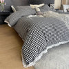 A black and white plaid duvet cover set with a lace trim is displayed on a bed.