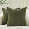 A textured olive green corduroy throw pillow cover with a geometric pattern resting on a white sofa.