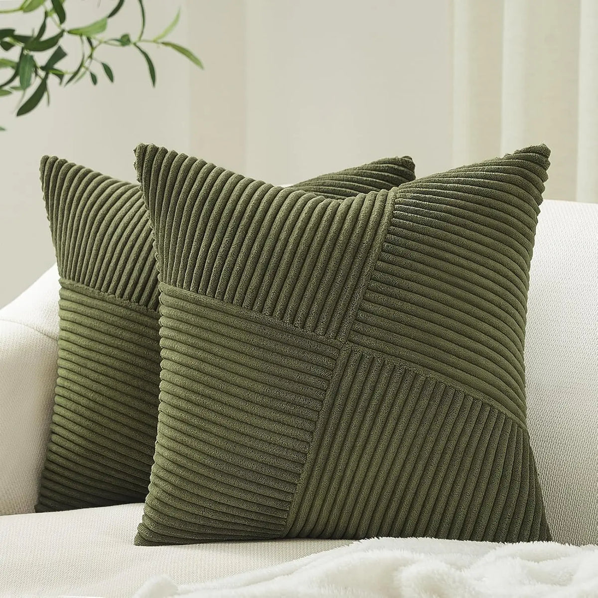 A textured olive green corduroy throw pillow cover with a geometric pattern resting on a white sofa.