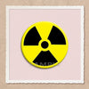 A yellow radiation symbol pin on a light pink background.