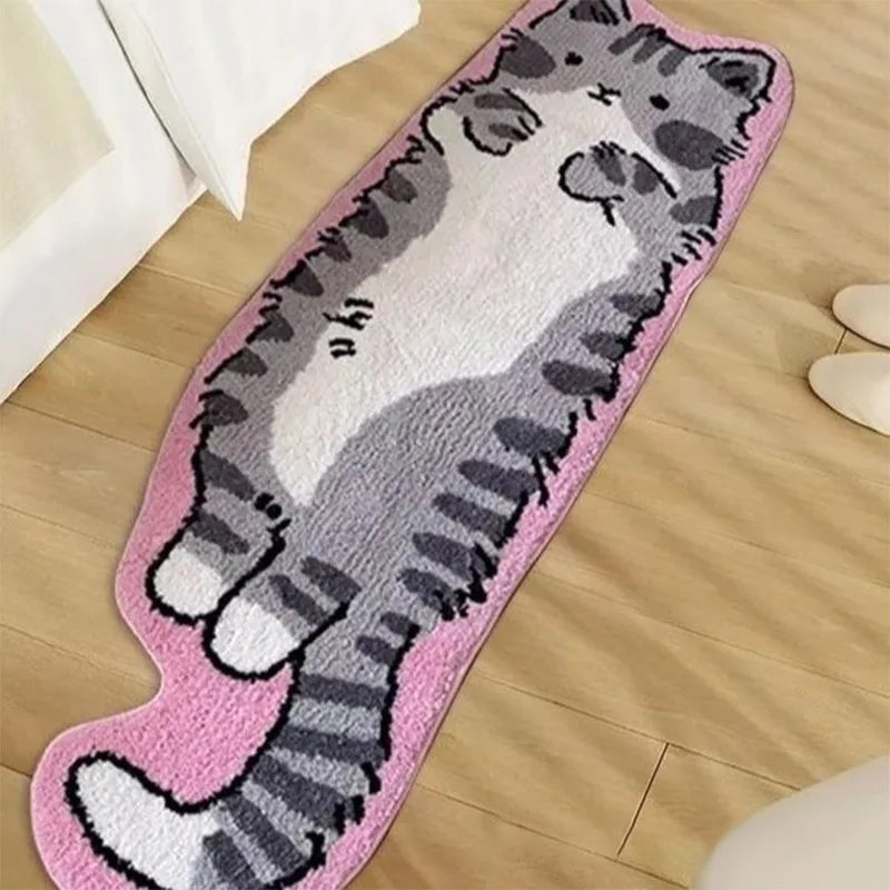 A pink decorative cat mat featuring a gray and white striped cat design placed on a wooden floor.