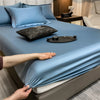 A light blue fitted bed sheet is draped over a bed, with a hand adjusting the fabric.