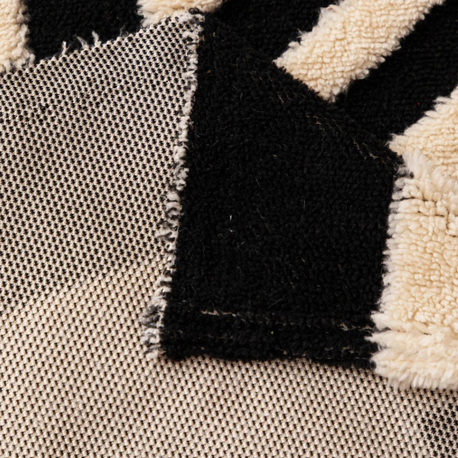 Close-up of a vintage bohemian knit sofa protector featuring black and cream geometric patterns.