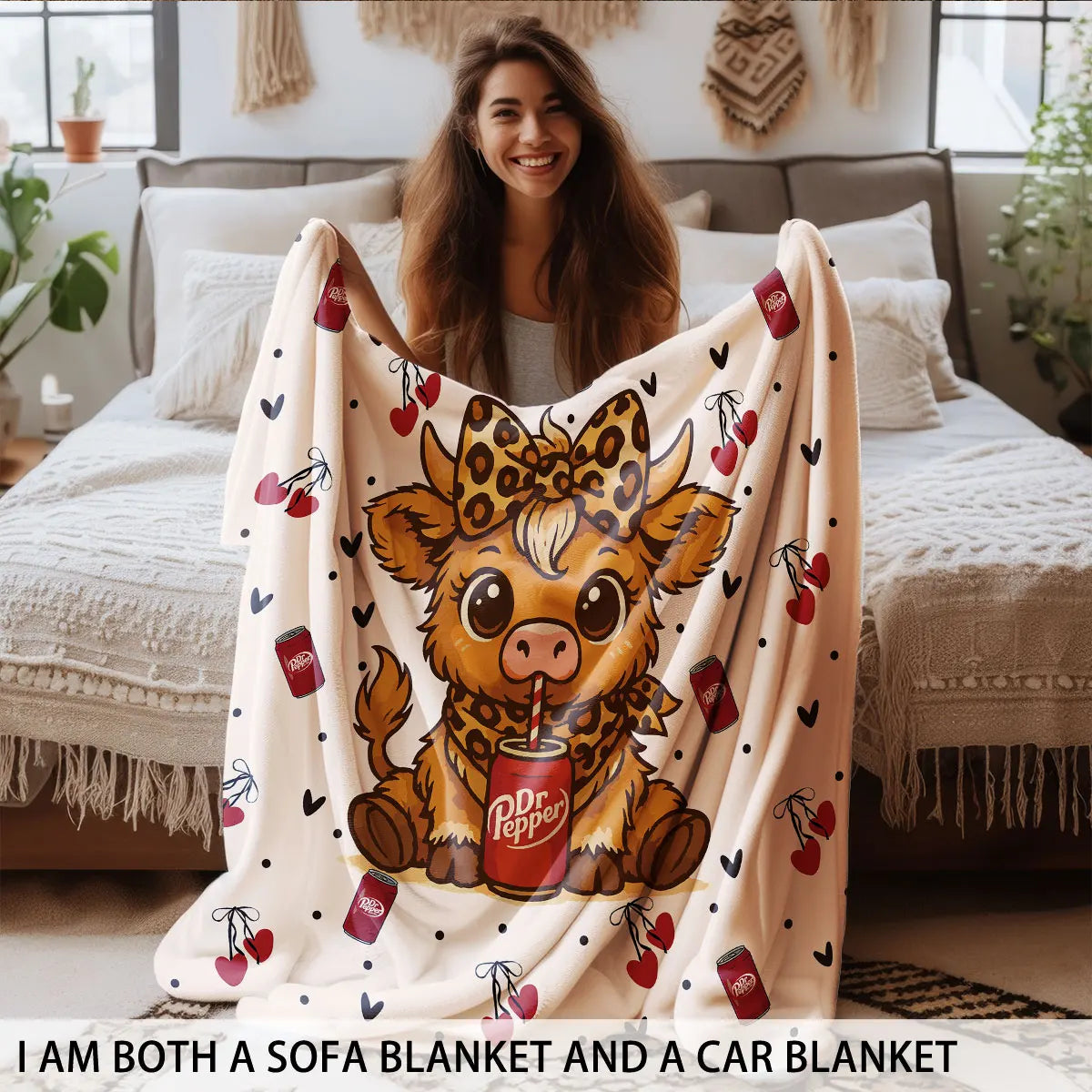 A woman is smiling while holding a tan and brown cartoon highland cow print flannel blanket.