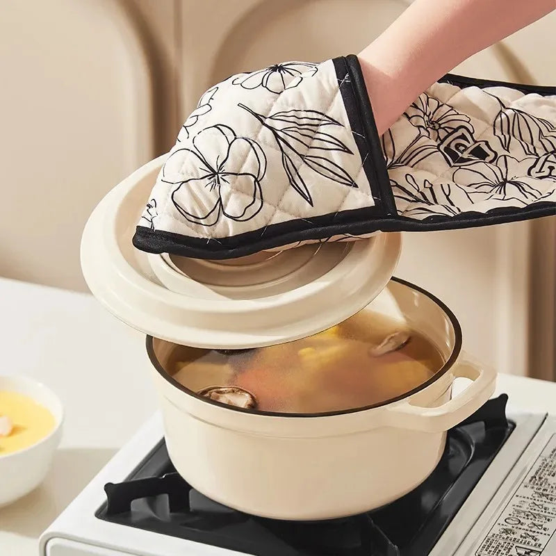 A hand wearing a floral patterned heat-resistant oven mitt is holding a ceramic pot of liquid in a baking context.