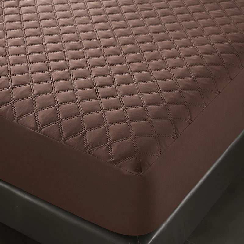 A close-up view of a brown quilted mattress protector on a dark bed frame.