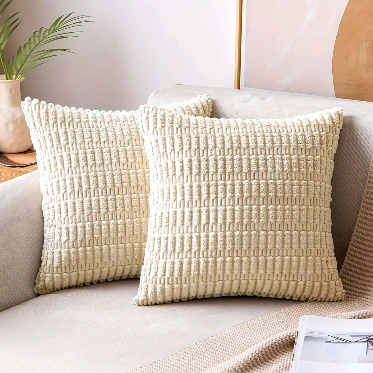 A cream colored corduroy decorative throw pillow cover with a subtle stripe design resting on a light-colored sofa.