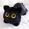 A black plush cat with large yellow eyes lying on a white surface.