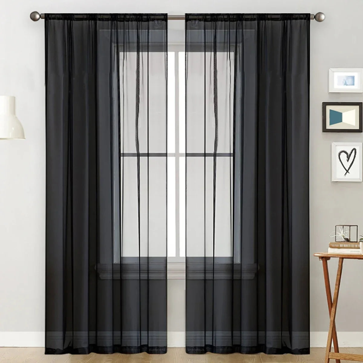 Black sheer curtain with a rod pocket hanging over a window.